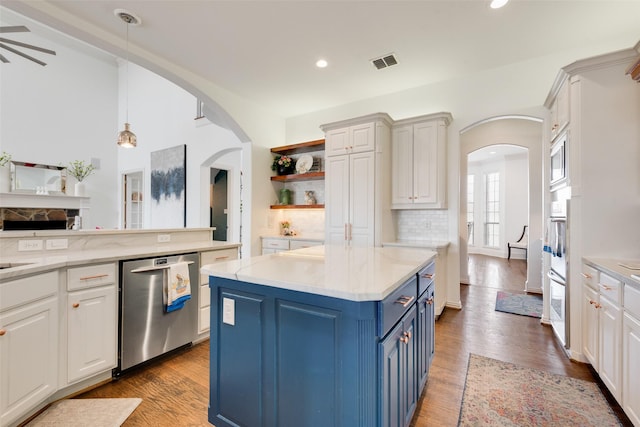 kitchen with blue cabinets, visible vents, light wood-style flooring, stainless steel appliances, and arched walkways