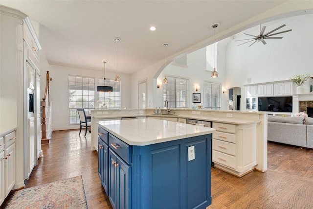 kitchen with open floor plan, blue cabinetry, arched walkways, and a spacious island