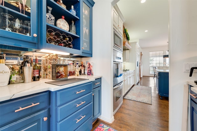 bar with recessed lighting, dark wood-type flooring, appliances with stainless steel finishes, and a bar