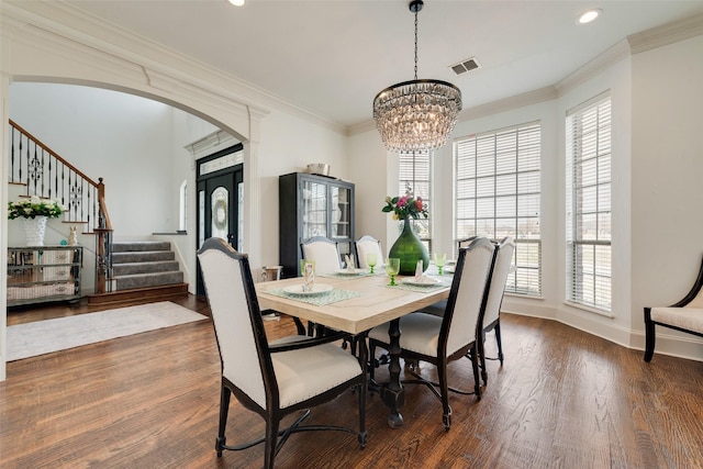 dining area with arched walkways, visible vents, stairway, and dark wood-type flooring