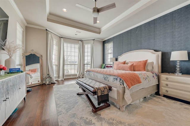 bedroom with wood finished floors, recessed lighting, ceiling fan, crown molding, and a raised ceiling