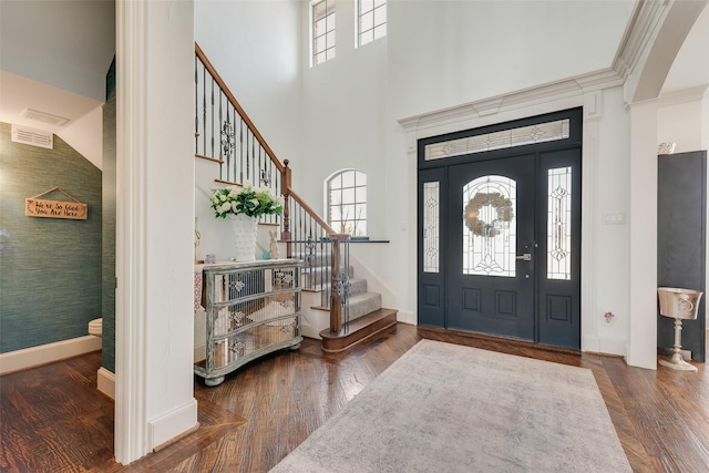 entrance foyer featuring stairs, a high ceiling, wood finished floors, and baseboards