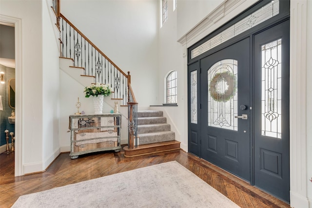 foyer entrance with a healthy amount of sunlight, a high ceiling, baseboards, and wood finished floors