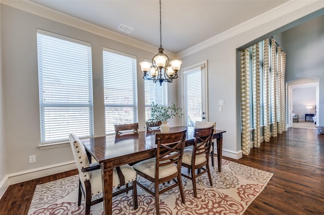 dining space with ornamental molding, wood finished floors, arched walkways, and a healthy amount of sunlight