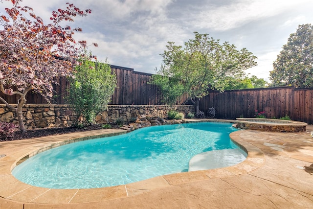 view of swimming pool featuring a patio, a pool with connected hot tub, and a fenced backyard