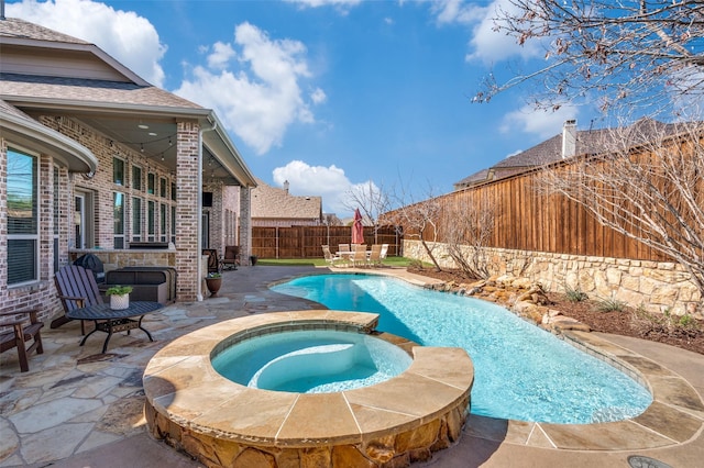 view of pool with a fenced backyard, a pool with connected hot tub, and a patio