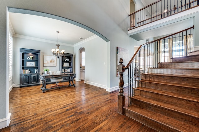 entrance foyer with baseboards, arched walkways, a notable chandelier, and wood finished floors