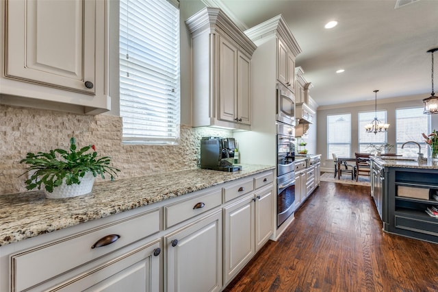 kitchen with stainless steel microwave, light stone countertops, a notable chandelier, dark wood-type flooring, and backsplash