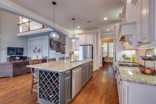 kitchen featuring arched walkways, appliances with stainless steel finishes, a sink, gray cabinetry, and visible vents