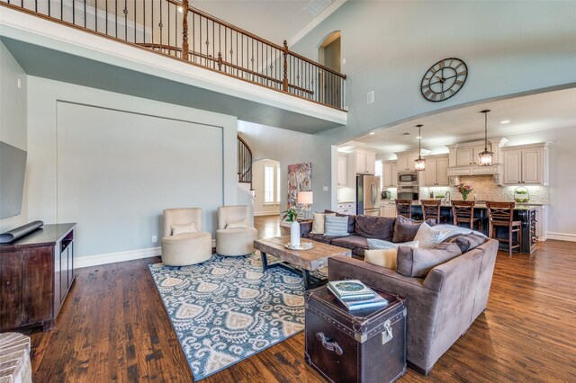 living area featuring dark wood finished floors, crown molding, stairs, and baseboards