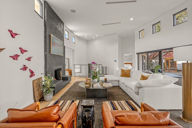 living room with a high ceiling, recessed lighting, and a large fireplace