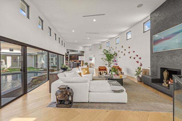 living area with a premium fireplace, a towering ceiling, and wood finished floors