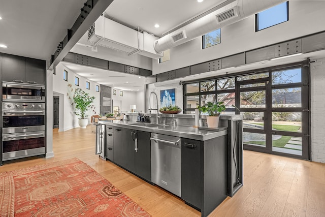 kitchen featuring visible vents, stainless steel countertops, appliances with stainless steel finishes, dark cabinetry, and a sink