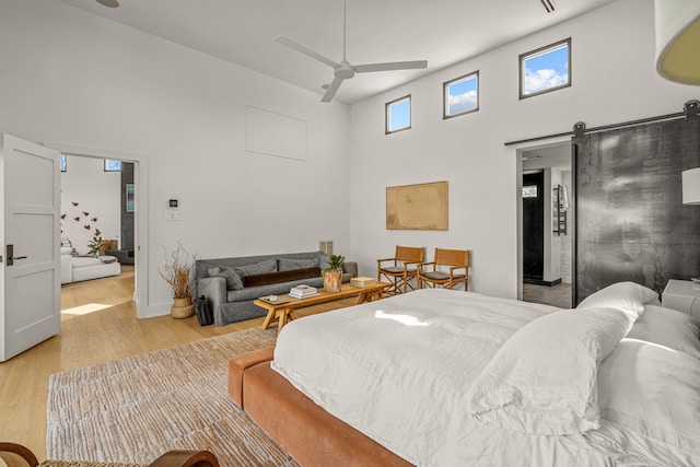 bedroom featuring a barn door, a high ceiling, and light wood-type flooring