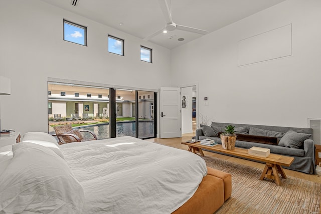 bedroom featuring a ceiling fan, a high ceiling, and light wood-style floors