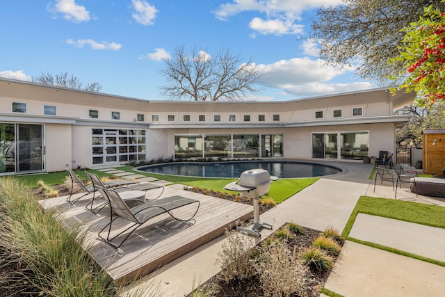 rear view of property with a patio area, an outdoor pool, and stucco siding