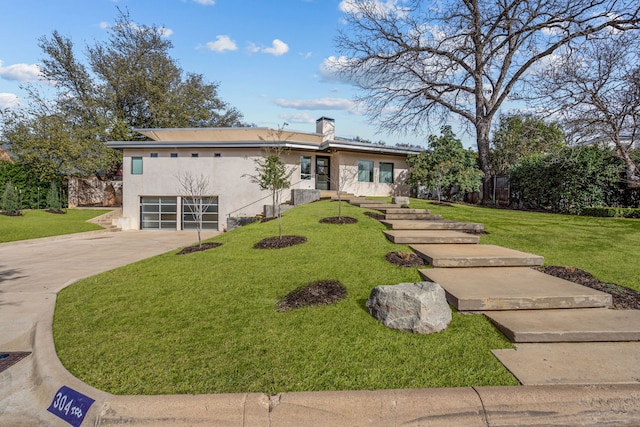 view of front of home with a front lawn, stucco siding, a chimney, a garage, and driveway