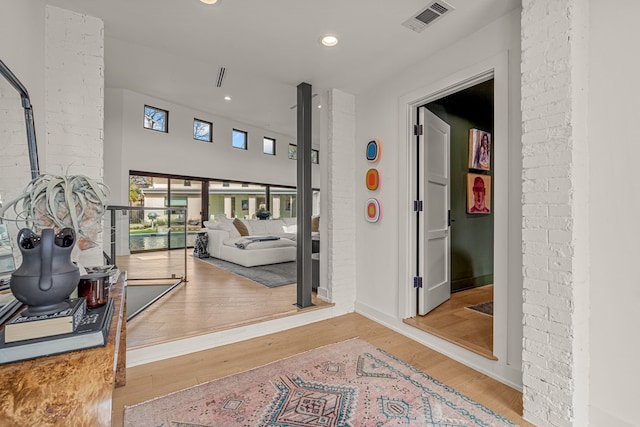 hallway featuring visible vents, recessed lighting, brick wall, and wood finished floors