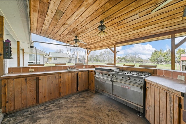 view of patio featuring a sink, a ceiling fan, and an outdoor kitchen