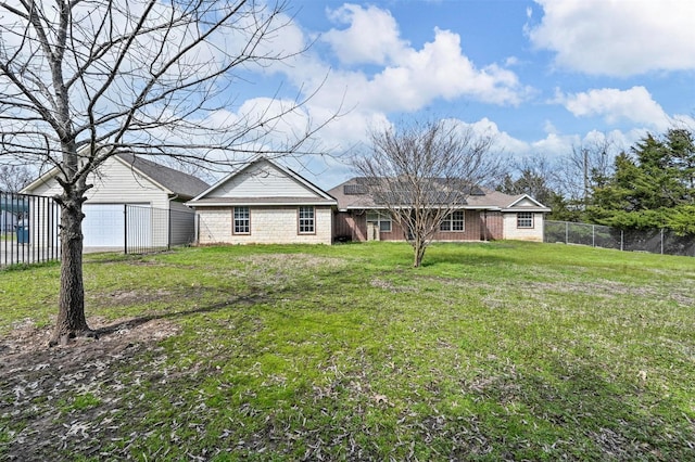 rear view of property featuring a lawn and fence