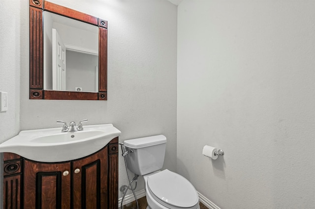 half bath with toilet, vanity, and baseboards