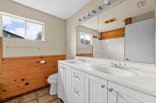 bathroom with a textured ceiling, toilet, visible vents, and a sink