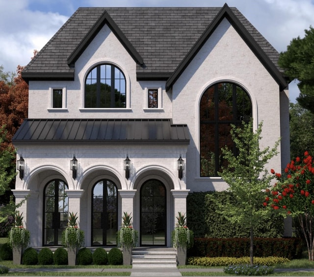 view of front facade featuring brick siding, metal roof, and a standing seam roof