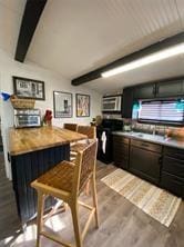 kitchen featuring stove, beamed ceiling, and dark wood-type flooring