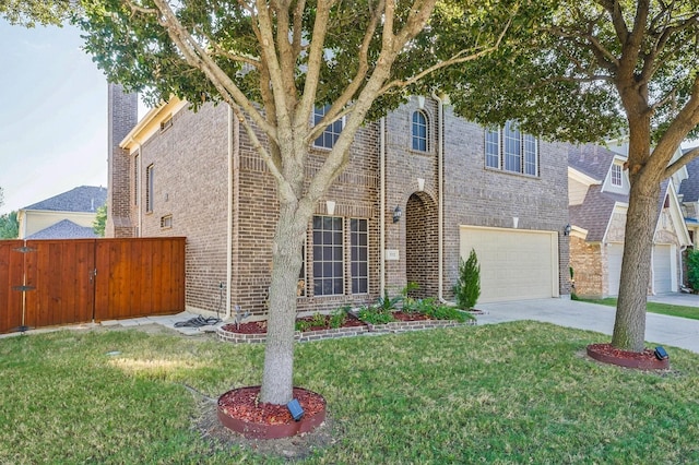 traditional-style house with a front yard, fence, concrete driveway, a garage, and brick siding