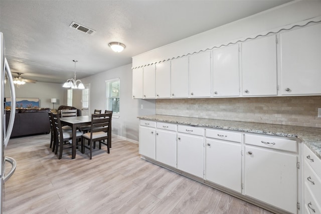 kitchen with visible vents, a textured ceiling, tasteful backsplash, white cabinetry, and light wood-style floors