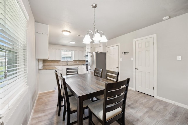 dining room featuring a chandelier, baseboards, visible vents, and light wood-style flooring