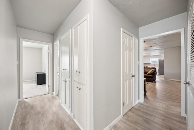 hall featuring light wood-style flooring and baseboards