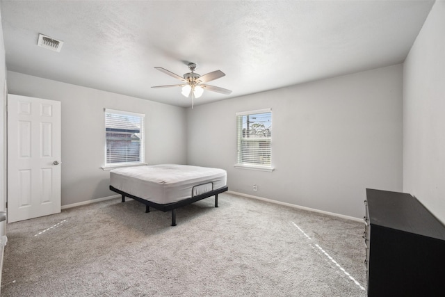 bedroom with visible vents, baseboards, ceiling fan, carpet flooring, and a textured ceiling