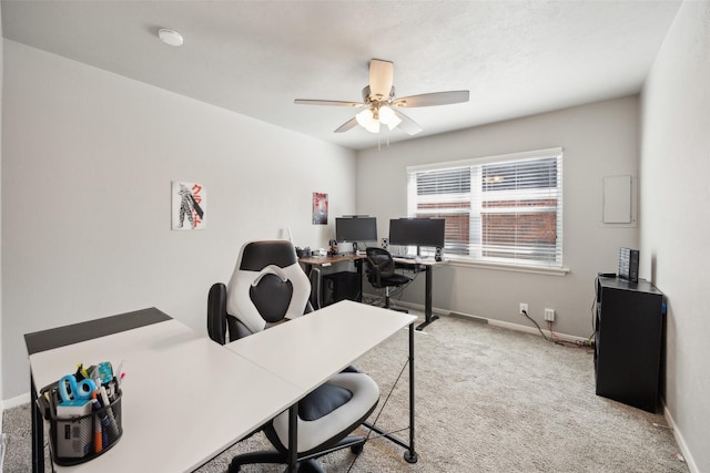 carpeted office space featuring baseboards and ceiling fan