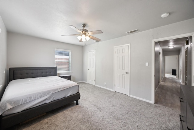 bedroom featuring visible vents, baseboards, multiple closets, carpet flooring, and a ceiling fan