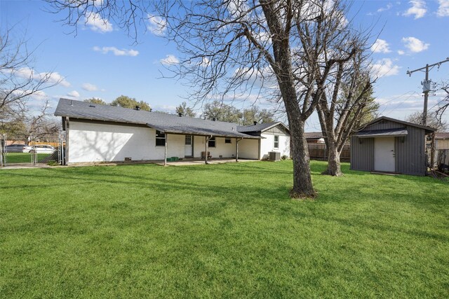 back of house with an outdoor structure, fence, a lawn, and a shed