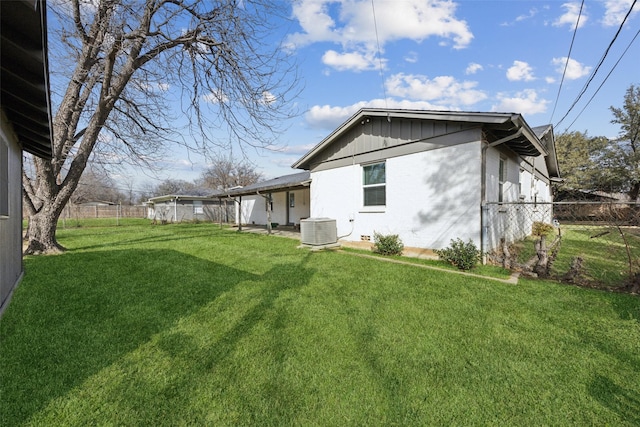 exterior space featuring central AC unit, a lawn, and fence