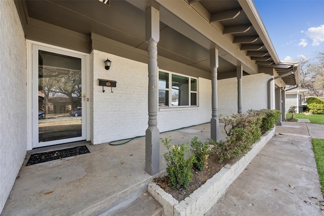 doorway to property with brick siding and covered porch