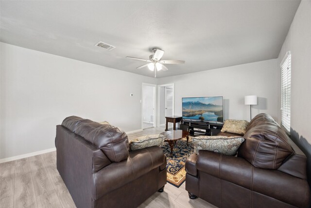 living room featuring a ceiling fan, light wood-style floors, visible vents, and baseboards