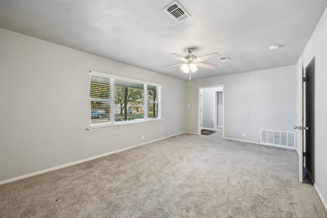 carpeted spare room with visible vents, a ceiling fan, and baseboards