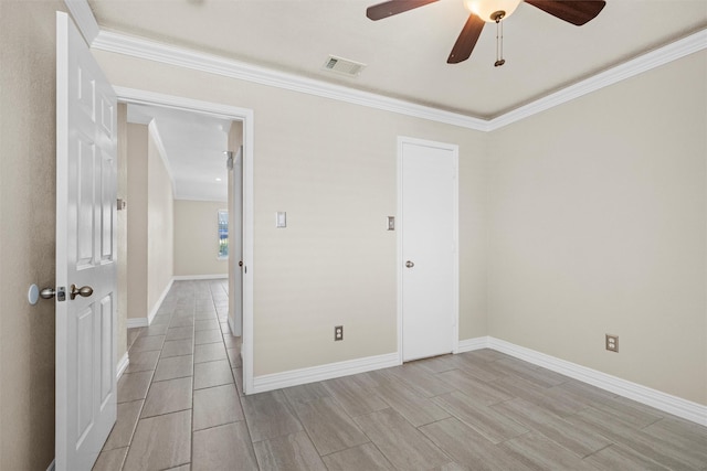 spare room featuring visible vents, a ceiling fan, crown molding, and baseboards