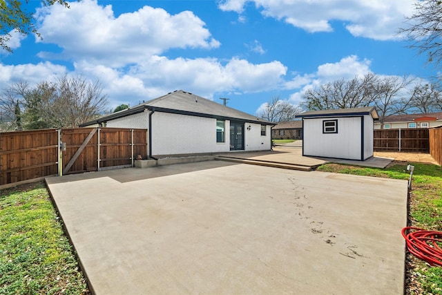 rear view of house featuring brick siding, a storage shed, a fenced backyard, an outdoor structure, and a patio