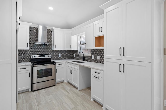 kitchen with stainless steel electric stove, decorative backsplash, white cabinets, wall chimney exhaust hood, and a sink