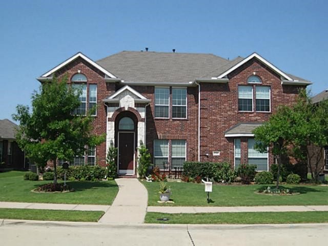 view of front facade with brick siding and a front lawn