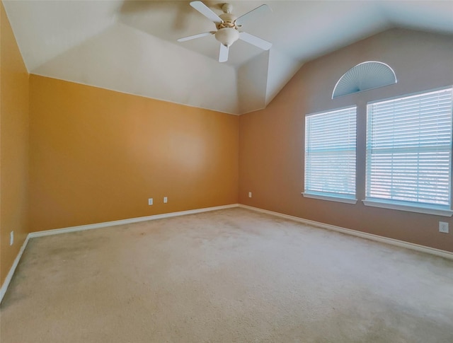 empty room with vaulted ceiling, a ceiling fan, baseboards, and carpet floors