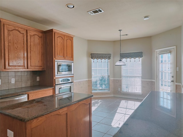 kitchen featuring light tile patterned flooring, visible vents, stainless steel appliances, and hanging light fixtures