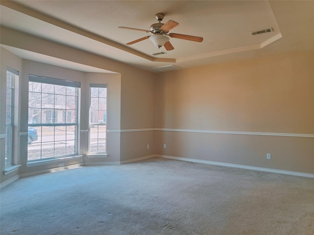 spare room featuring a raised ceiling, baseboards, visible vents, and carpet floors