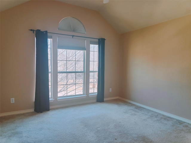 carpeted spare room featuring baseboards and vaulted ceiling