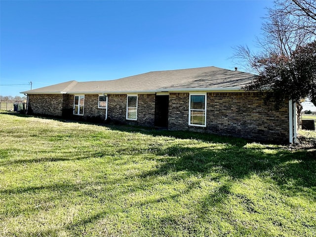 ranch-style home with a front lawn, brick siding, and roof with shingles