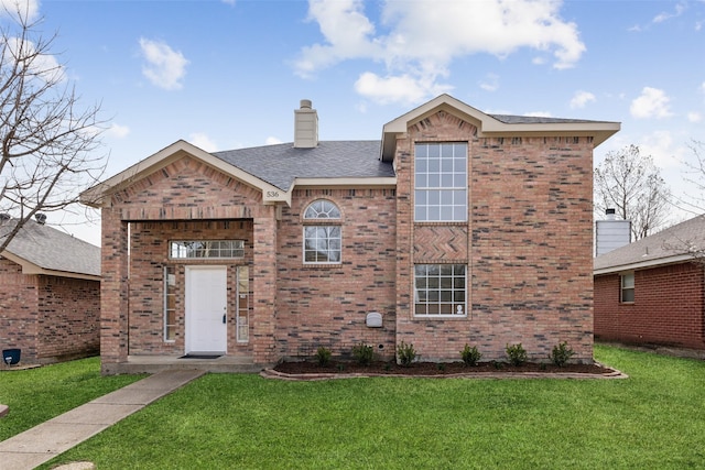 view of front of house featuring a shingled roof, a front lawn, brick siding, and a chimney